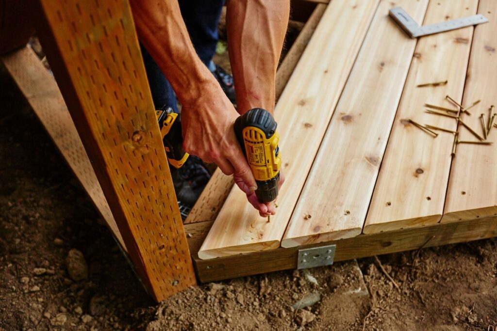 man drilling and measuring wood for deck