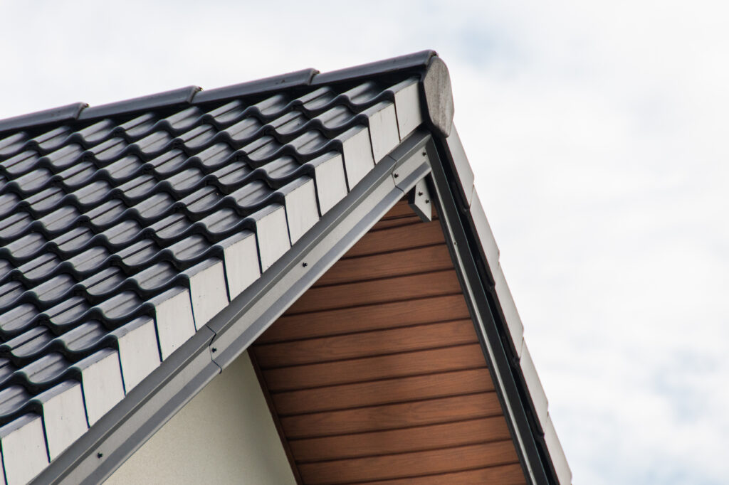 Stylish roof detailing with black tiles, wooden eaves, and a clear sky background, highlighting contemporary residential architecture.