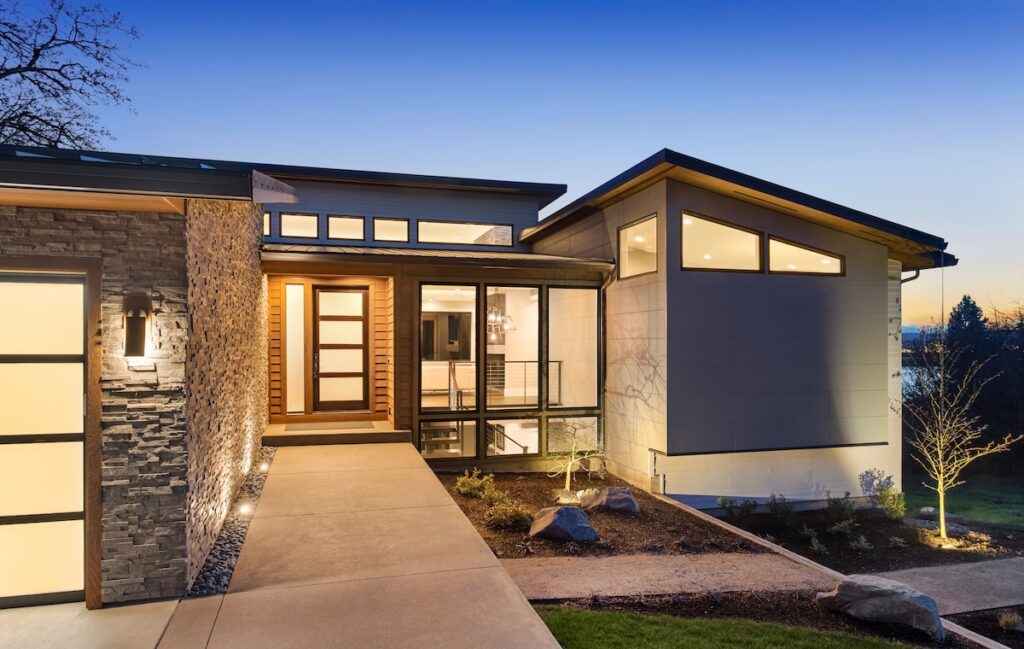 modern roof Beautiful modern style luxury home exterior at sunset with glowing interior lights.