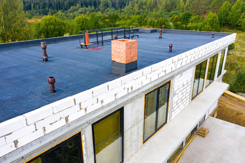 flat roof leak repair Roof waterproofing. Building construction. A protective layer was applied on the roof of the house. Installation of a waterproofing layer. Construction works. Bitumen insulating layer.