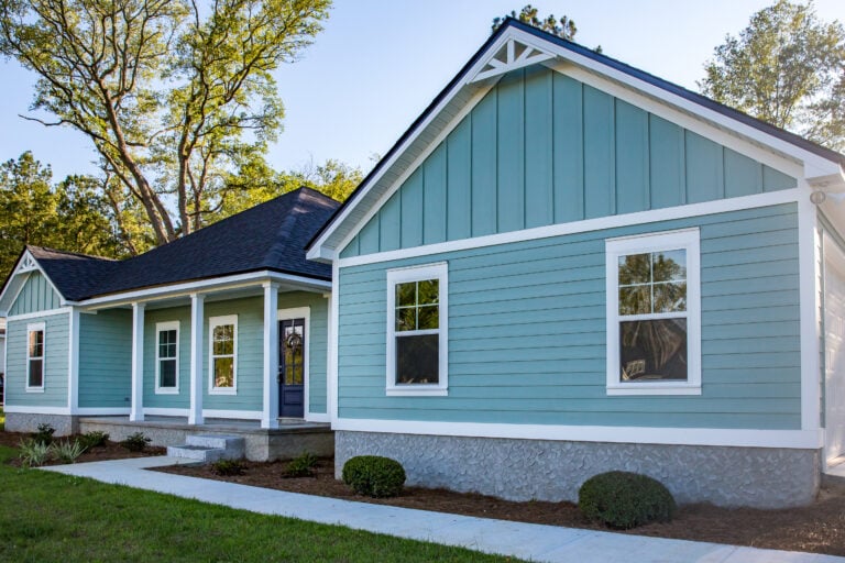 Front view of a brand new construction house with blue siding, a ranch style home with a yard