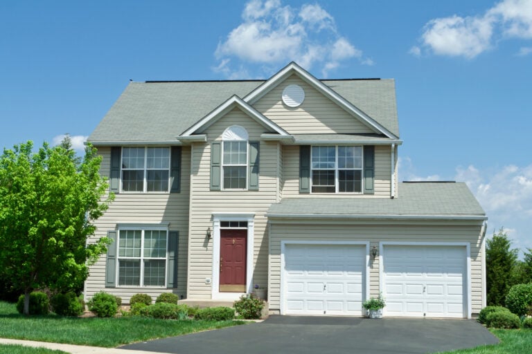 Modern vinyl sided single family home in suburban Maryland. House has two car garage, driveway and red door.
