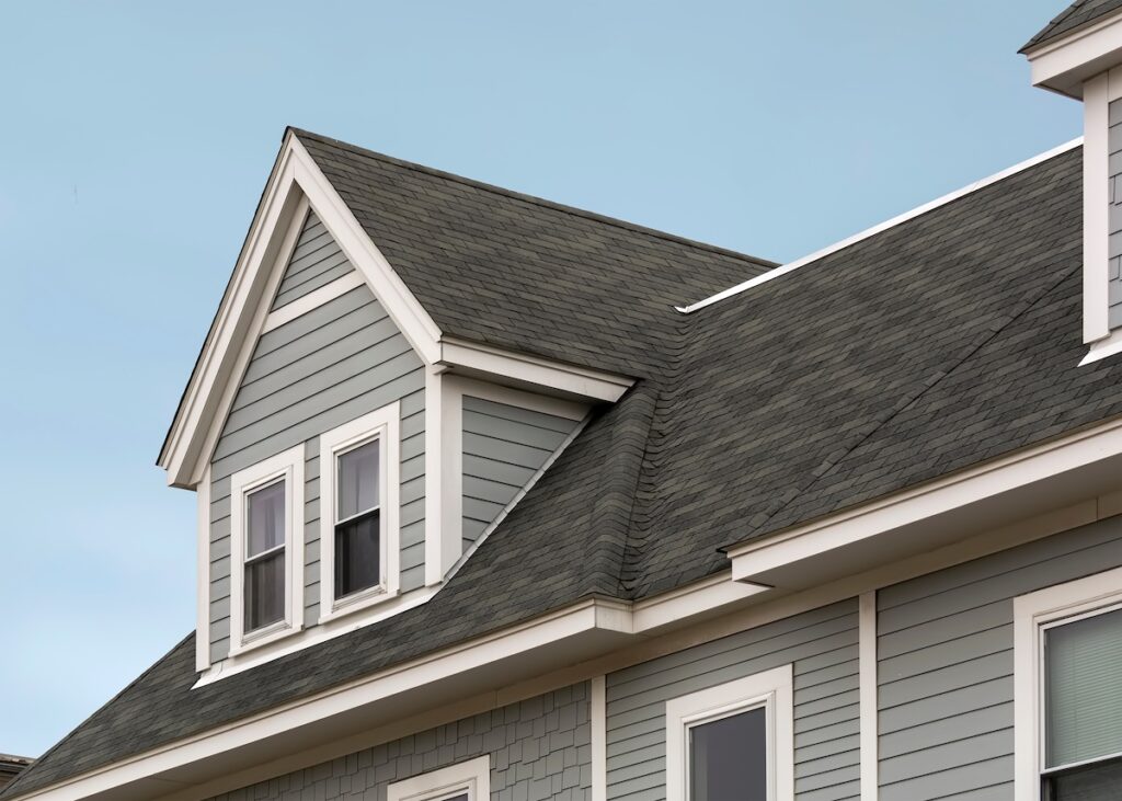 roofing insurance Detailed view of a gable-style dormer window on a sloped roof of a newly built family house