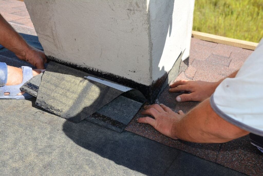 A close-up on a roofing construction, installation of asphalt shingles on roof sheathing around a house chimney