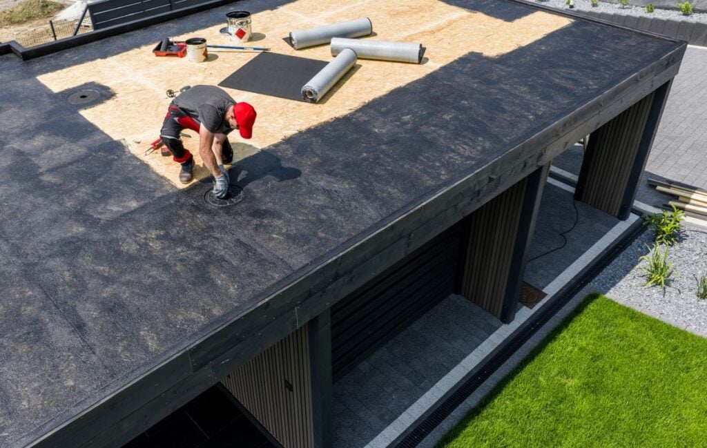 epdm rubber roof male worker installing coat on big house during daylight