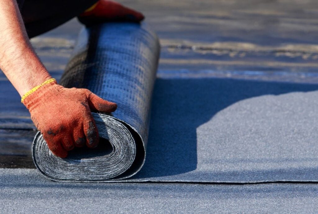 Worker puts roofing material on a flat roof