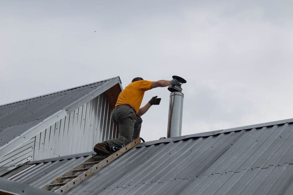 chimney cap man installing galvanized piece