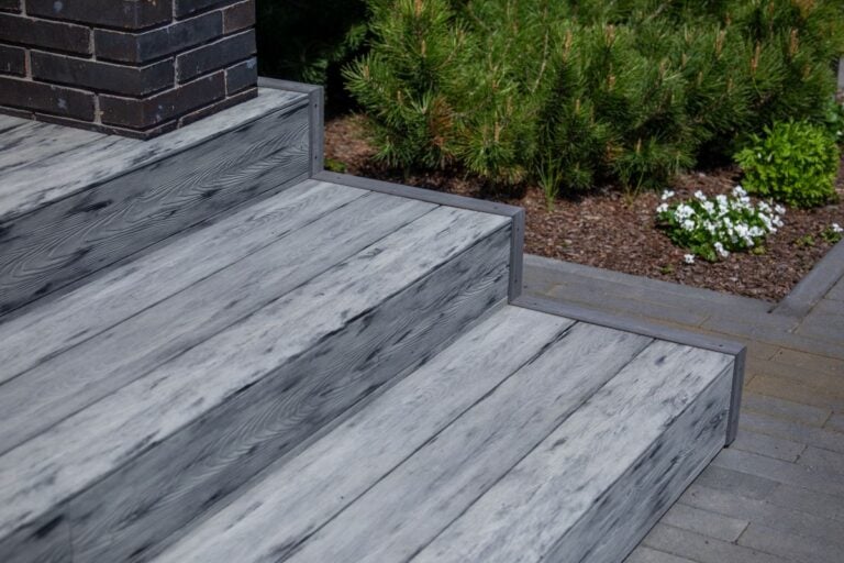 Gray composite deck stairs next to dark brick column
