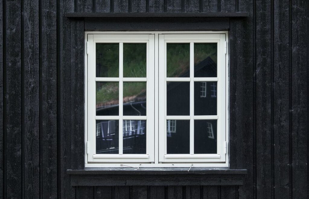 Colonial style casement window of white painted wood on a black house