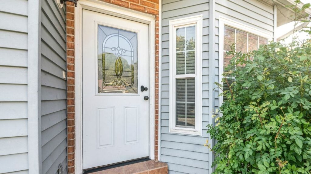 Front door exterior with bricks and vinyl siding wall
