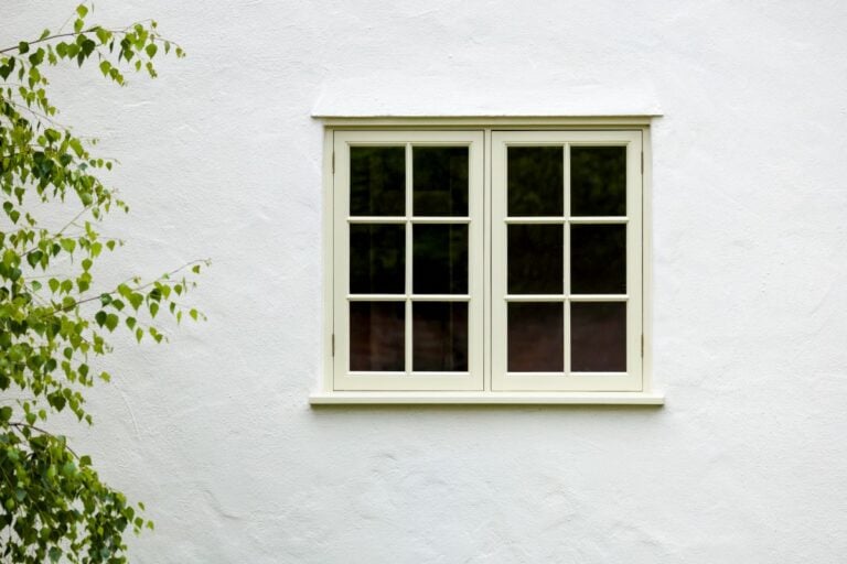 white house with a beige casement window next to a tree