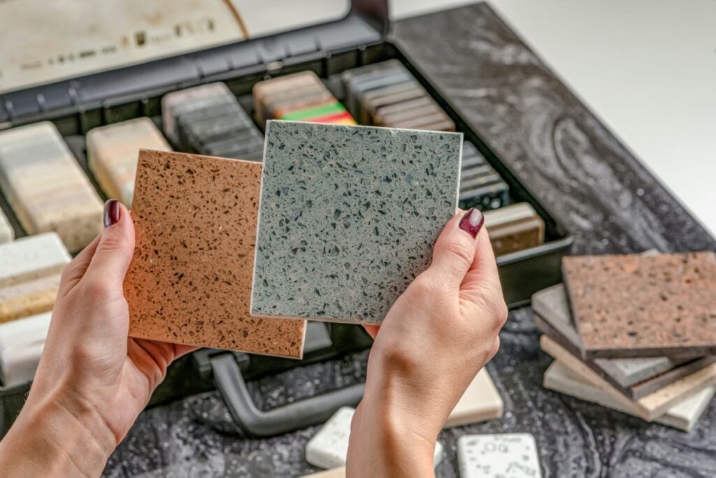 Samples of material for the countertop. Female hands are choosing interior elements for renovation.