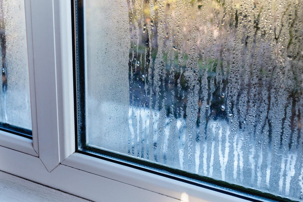 Fragment of a plastic window with water condensation on the glass