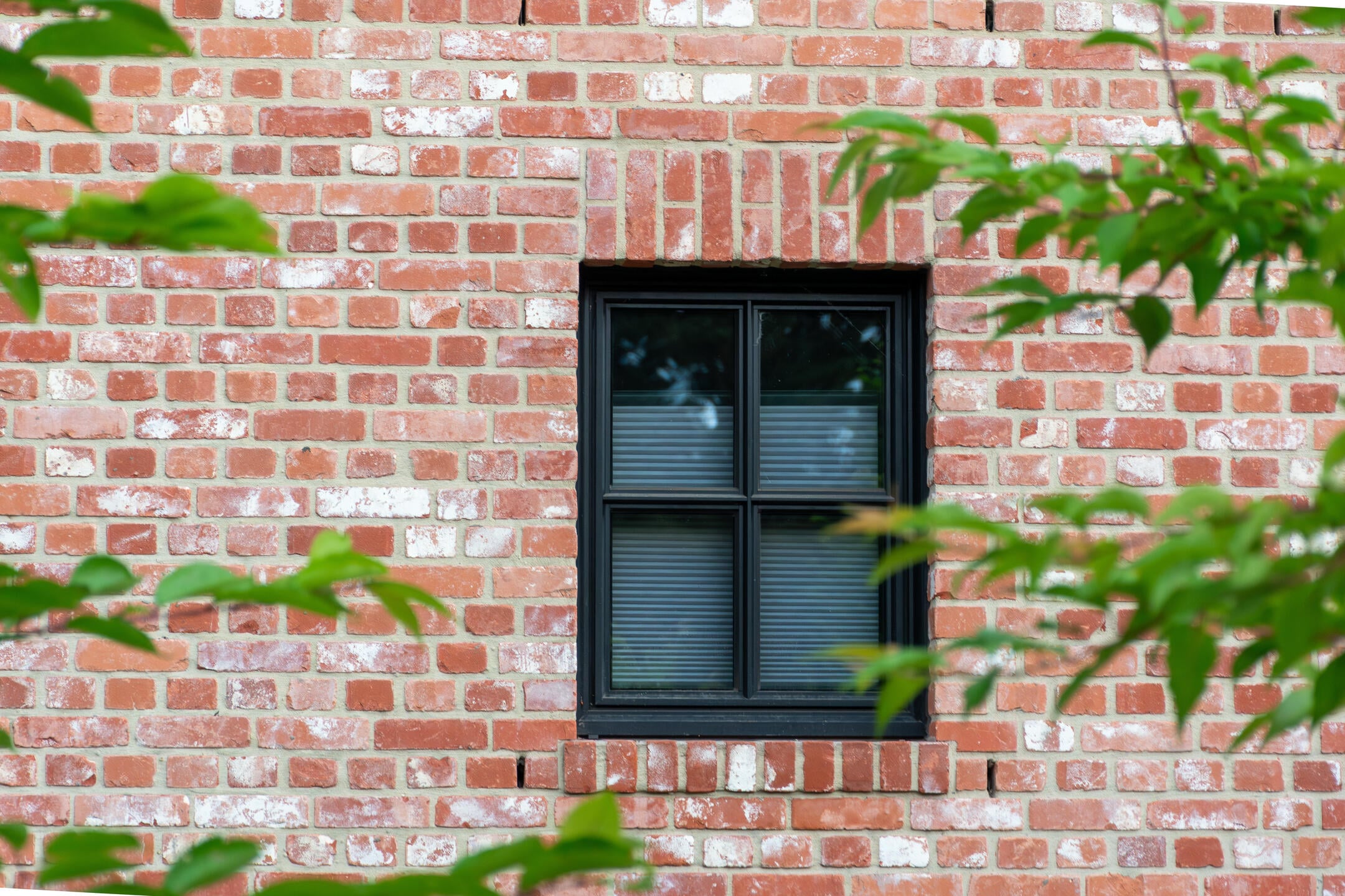 Modern black window frame on an old red brick wall